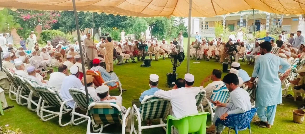 A large gathering of tribal elders, local leaders, and officials seated outdoors in traditional attire, engaged in discussions during the Bajaur Grand Jirga aimed at promoting peace and addressing security concerns. [File Photo].