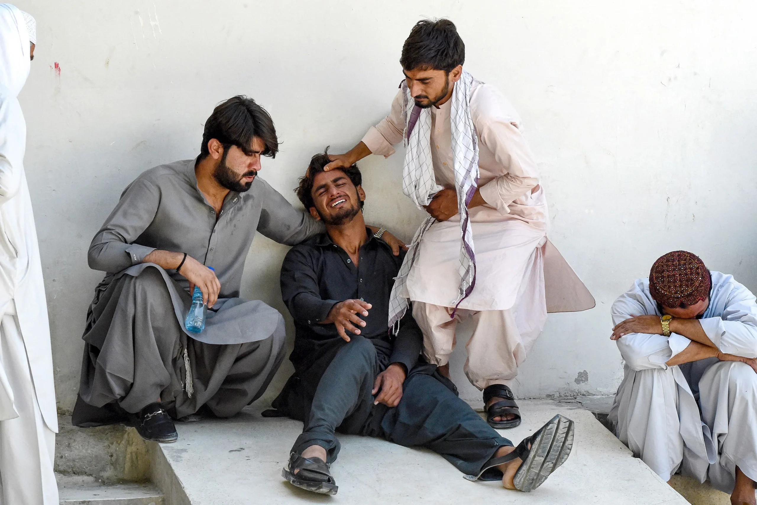 A man (2L) mourns the death of his father, who died in a separatist militants shooting, at a hospital in Quetta on August 26, 2024. [IC: Banaras Khan/AFP/Getty Images]