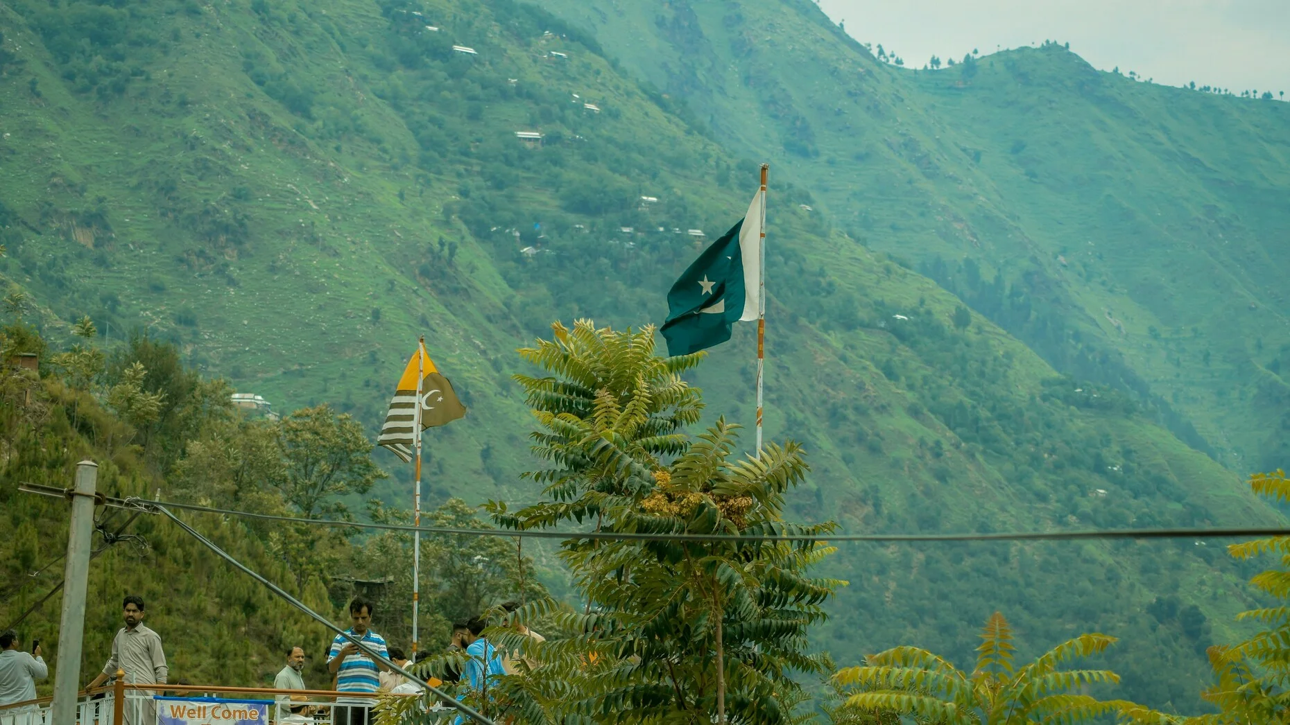 Pakistani and Azad Kashmir flags wave against the lush green hills of Kashmir amid renewed India-Pakistan tensions following the Pahalgam attack. [IC: File Photo]