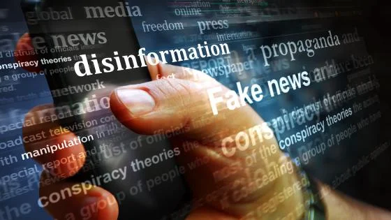 A close-up of a person using a smartphone, overlaid with digital words like “disinformation,” “Fake news,” “propaganda,” “manipulation,” and “conspiracy theories,” symbolizing the spread of false information and media manipulation.